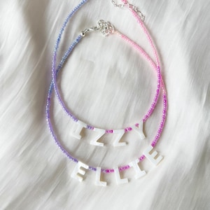 Collar con nombre o palabra en degradado rosa pastel y morado con cuentas de letras de nácar; cierre bañado en plata, plata de ley o relleno de oro