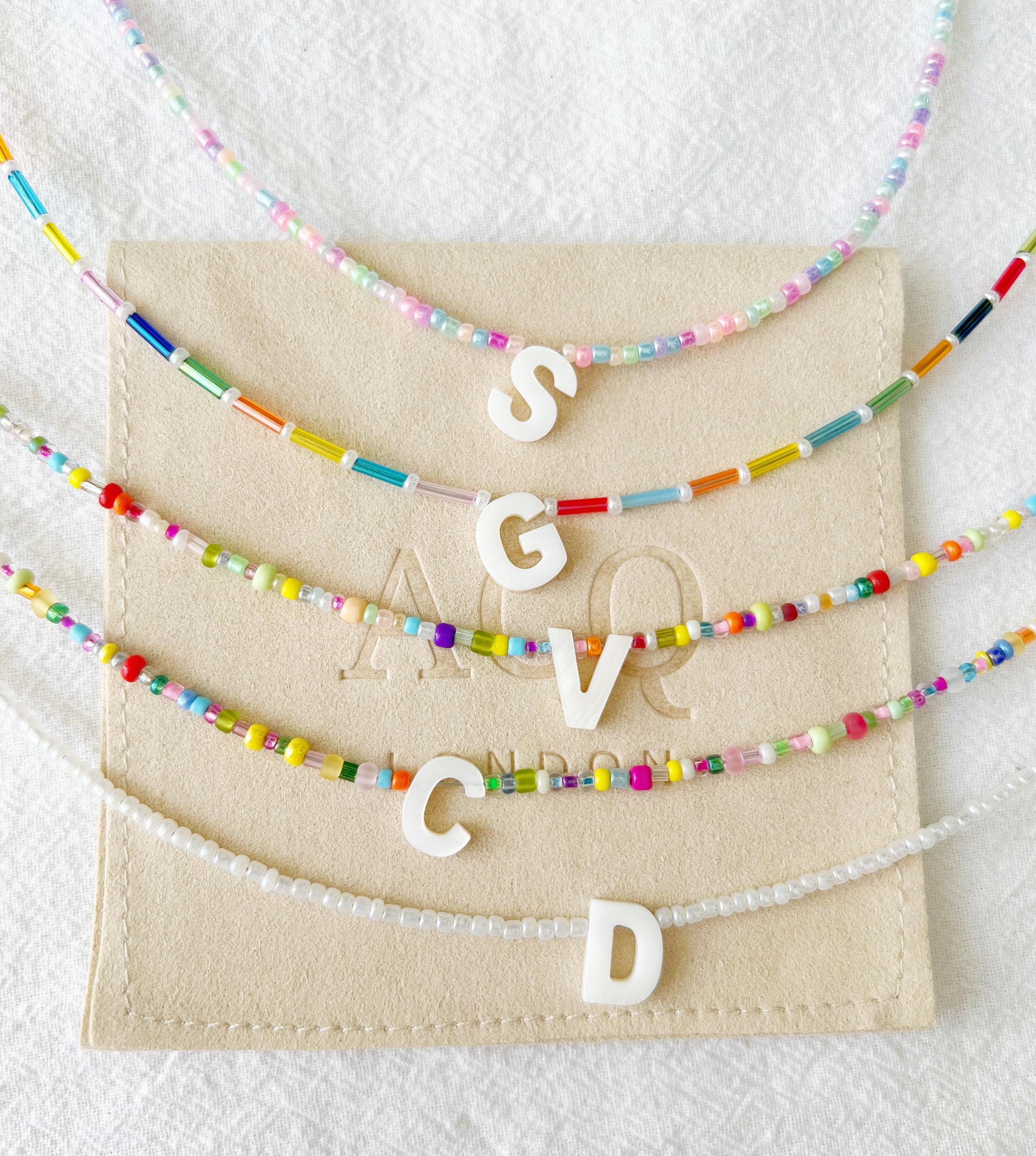 VENTA DE MUESTRAS: collar de cuentas con inicial, una cuenta de letra de nácar y 33 opciones de color; cierre plateado y cadena de extensión.