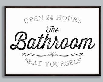 May include: A framed sign with a white background and black text. The sign reads "OPEN 24 HOURS The Bathroom SEAT YOURSELF" in a decorative font. The frame is dark brown.