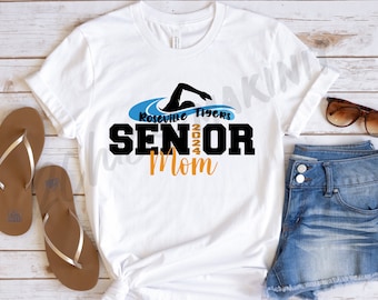 May include: White t-shirt with a blue and black graphic of a swimmer. The graphic includes the text "Roseville Tigers Senior Mom".