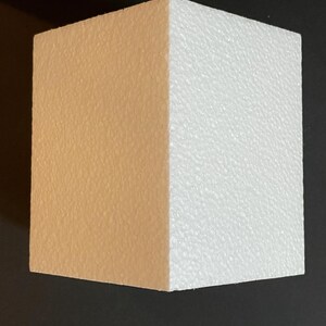 May include: A rectangular block of polystyrene with one side painted a light brown colour and the other side left white.