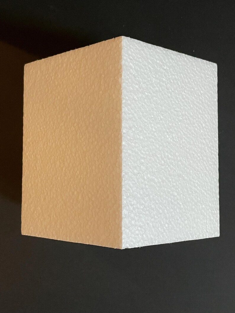 May include: A rectangular block of polystyrene with one side painted a light brown colour and the other side left white.