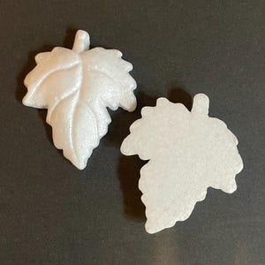 May include: Two white foam leaves, one with a more detailed vein pattern, are shown against a black background.
