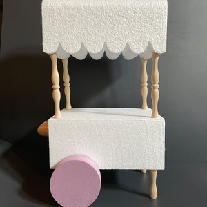May include: White foam craft cart with a scalloped canopy, wooden dowel legs, and a pink foam wheel. The cart is a blank canvas for decorating.