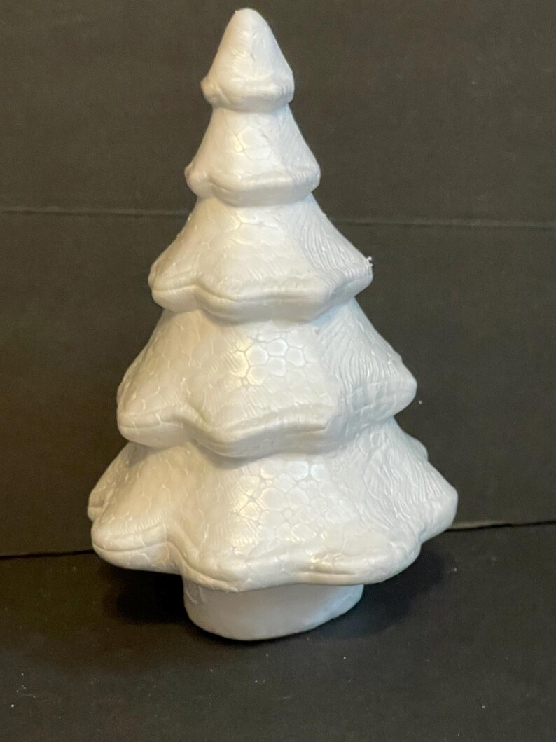 May include: A white polystyrene Christmas tree with a textured surface. The tree is approximately 15 cm tall and has a rounded base.