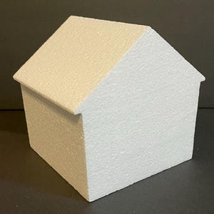 May include: A white polystyrene house shaped cake dummy. The cake dummy is a blank canvas for decorating.