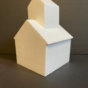 May include: A white polystyrene cake dummy shaped like a house with a smaller house on top. The cake dummy is ideal for practising cake decorating techniques.