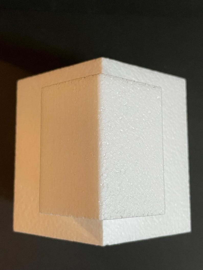 May include: White polystyrene cake dummy with a square base and a smaller square top. The top is offset from the base, creating a tiered effect.