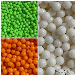 May include: Three different colors of small round balls. The balls are green, orange, and white.