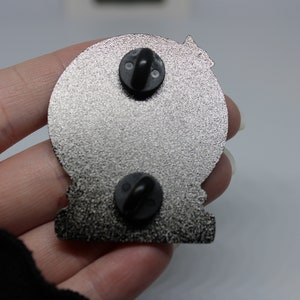 Peut inclure: L'arri&egrave;re d'une &eacute;pingle en m&eacute;tal argent&eacute; avec deux fermoirs papillon noirs. L'&eacute;pingle est en forme de cercle avec une surface textur&eacute;e.