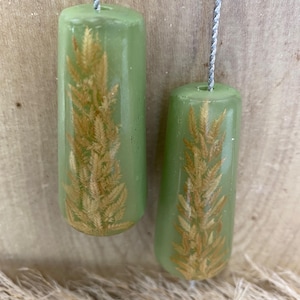 May include: Two cylindrical light green resin pulls with embedded dried golden wheat stalks, each attached to a thin silver cord. The pulls have a smooth, glossy finish and are suspended vertically, showcasing the natural botanical elements inside.