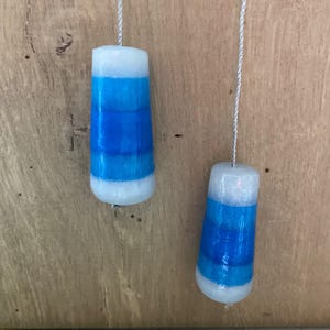 May include: Two white and blue striped glass light pull beads hanging from silver cords.