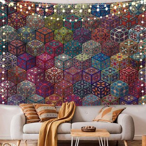 May include: A tapestry with a geometric pattern of colorful, intricate designs. The tapestry is made up of repeating hexagonal shapes, each with a unique pattern. The tapestry is hung on a wall above a couch with throw pillows and a blanket.