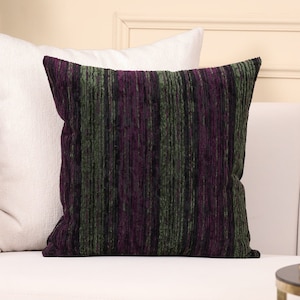 May include: A decorative throw pillow with a striped pattern in shades of black, purple, and green. The pillow is made of a soft, textured fabric.