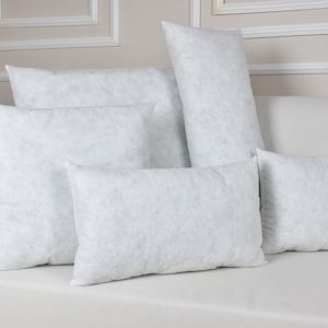 May include: Five white pillow inserts of various sizes are arranged on a white couch. The pillows are made of a soft, fluffy material and are perfect for adding comfort and support to any bed or sofa.