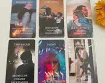 May include: A set of six tarot cards with various images and text. The cards feature illustrations of people and scenes, with titles such as "Two Faced" and "Today". The color palette includes blues, browns, and purples.
