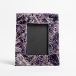 May include: A purple amethyst picture frame with a black mat. The frame is made of natural stone and has a unique, textured surface.