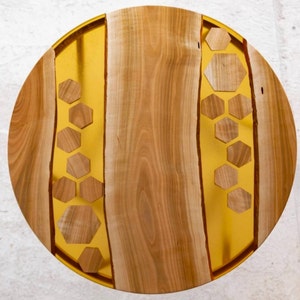 Pode incluir: Tampo de mesa redondo de madeira com incrustação de resina epóxi dourada com um padrão de favo de mel. O tampo da mesa é feito de madeira natural com um padrão de grão único.