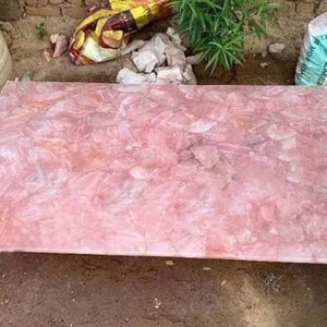 May include: A large, rectangular slab of pink quartz, with a smooth, polished surface. The quartz is made up of many smaller pieces, creating a unique and beautiful pattern.