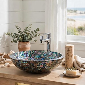 Pode incluir: Uma cuba redonda com um mosaico de azulejos de concha de abalone iridescentes em tons de azul, verde e roxo. A cuba está montada num móvel de madeira clara com uma placa de latão com a inscrição Royal Handicraft Expo e uma torneira cromada.
