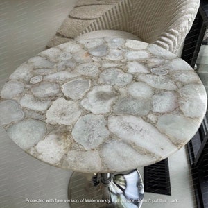 May include: A round, white agate table top with a polished chrome base. The table top is made of many small, irregular pieces of agate, each with a unique pattern.