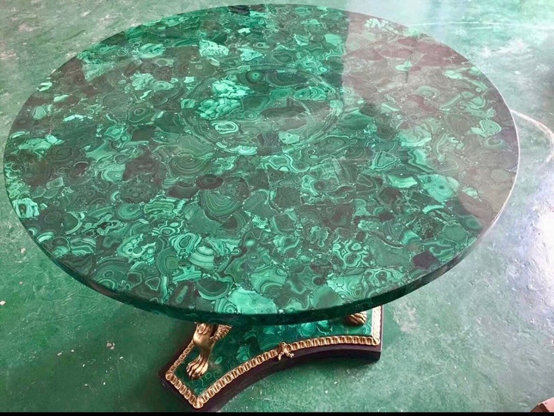 May include: A round table with a green malachite top and a gold-painted base with lion paw feet.