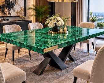 May include: A rectangular dining table with a polished green malachite stone top and a black metal X-shaped base. A small rectangular brass plaque with the text Royalhandicraftexpo is attached to the side of the table edge. Six beige upholstered chairs.
