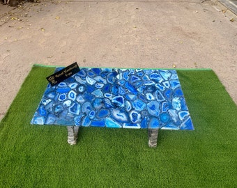 May include: Blue agate coffee table with a glass top and metal legs. The table is on a green artificial grass surface. The label on the table reads "Royal Handicraft Expo".