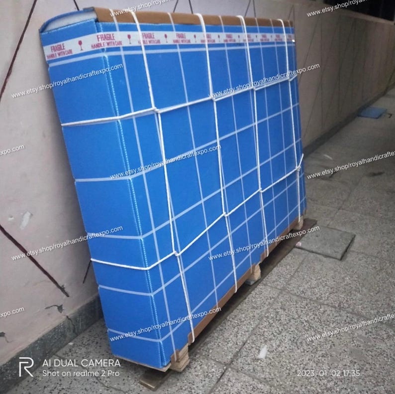 Pode incluir: Uma caixa grande azul com um padr&atilde;o de grade branca &eacute; fixada com tiras brancas. A caixa est&aacute; etiquetada como "Fr&aacute;gil Manusear com cuidado" e tem o endere&ccedil;o do site "www.etsy.shop/royalhandicraftexpo.com" impresso nela.