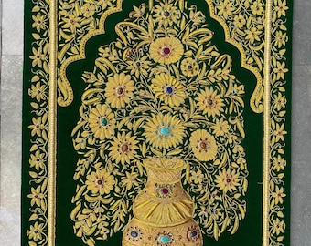 Puede incluir: Un tapiz de pared de terciopelo verde con un diseño floral bordado en oro y un jarrón adornado con joyas de colores. El jarrón está en el centro del diseño y las flores están dispuestas a su alrededor.