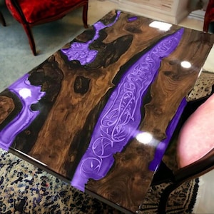 Könnte beinhalten: Eine Tischplatte aus dunklem Holz mit einer violetten Harzeinlage. Das Harz hat ein wirbelndes Muster und ist glänzend.