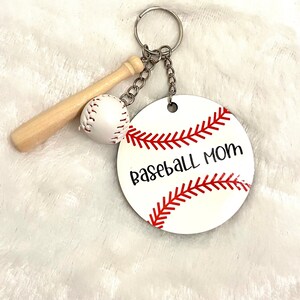 May include: White and red baseball-themed keychain with a wooden bat, a white baseball, and a round tag that says "Baseball Mom".