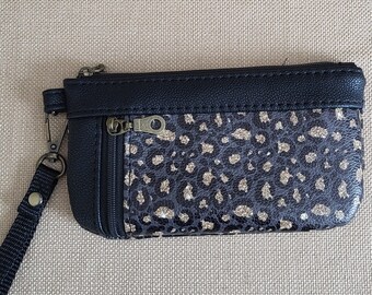 Leopard skin printed vinyl zippered wallet/wristlet with 2 pockets, black faux leather accents and wristlet strap. 7" x 3.75"