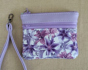 Delicate Lavender and mauve flowers adorn this zippered wallet/wristlet, with 2 pockets, lavender accents and wristlet strap. 5.25" x 4."