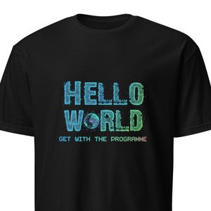 Op de afbeelding: Zwart t-shirt met de tekst "HELLO WORLD" in blauw en groen, met een pixelachtige wereldbol. Daaronder staat de zin "GET WITH THE PROGRAMME". Het t-shirt heeft een ronde hals.