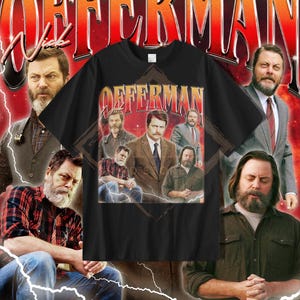 May include: Black t-shirt with a vintage-style design featuring the name "OFFERMAN" and a collage of images of a man. The background has a red and white lightning bolt design. The t-shirt is a classic crew neck.