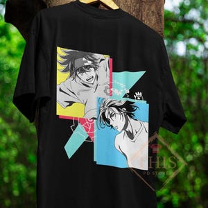 Puede incluir: Camiseta negra con un estampado gráfico de dos personajes de anime en formas geométricas coloridas. Los personajes están en blanco y negro, y las formas están en tonos de azul, rosa, amarillo y verde.