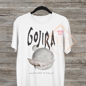 May include: White t-shirt with a black graphic of the band Gojira. The graphic includes a whale swimming around a planet with the text "From Mars to Sirius".