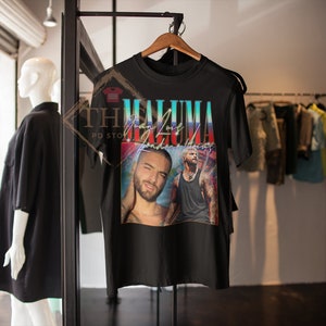 May include: Black t-shirt featuring a vintage-style graphic of singer Maluma. The graphic has a colourful background with the text "Maluma" and "Man of My Dreams" in a stylised font.