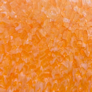 May include: Abstract close-up of an orange and white textured surface. The surface has a mosaic-like appearance, with irregular shapes and a mix of orange and white hues. The texture is rough and uneven.
