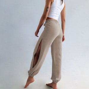 Indulge in the perfect fusion of natural comfort and bohemian elegance with these beige pants, meticulously crafted from 100% cotton. Their high-waist design, side slit, and tie belt seamlessly combine fashion with practicality.