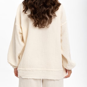 May include: A white cotton lounge set with a long-sleeved top and trousers. The top has a relaxed fit and a slightly frayed hem. The trousers have a straight leg.