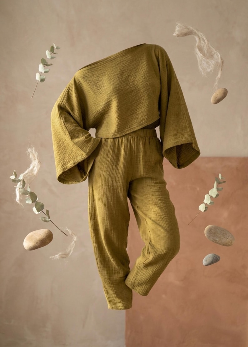 May include: An olive green two-piece set consisting of a loose-fitting, long-sleeved cropped top with wide sleeves and matching high-waisted trousers with a tapered leg. The fabric has a visible crinkled texture throughout the entire garment.