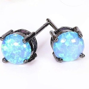 May include: A pair of black stud earrings with blue opal stones. The earrings have a simple design and are perfect for everyday wear.