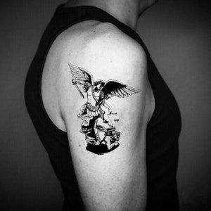 Puede incluir: Tatuaje temporal en blanco y negro de un ángel con alas, sosteniendo una espada y de pie sobre un demonio.