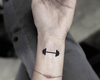 Premium Photo Hand woman with a dumbell on the gyms floorno pain no gain tattoo