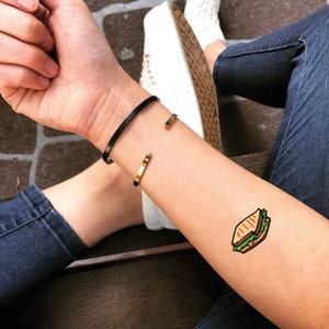 May include: A temporary tattoo of a cartoon sandwich on a person's arm.