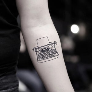 Puede incluir: Un dibujo en blanco y negro de una máquina de escribir vintage con una hoja de papel en blanco en el carro.