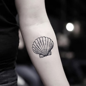 Puede incluir: Un dibujo en blanco y negro de una concha en el brazo de una persona.