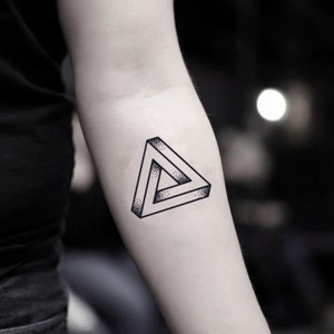 May include: A black and white temporary tattoo of an optical illusion triangle.